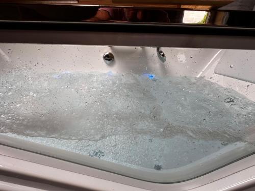 a bath tub filled with water with two water drops at Chalet Bois de Rose in La Bresse