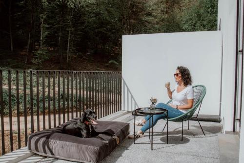 a woman sitting in a chair next to a dog at Boutique Hotel GreenLeaf in Sinzing
