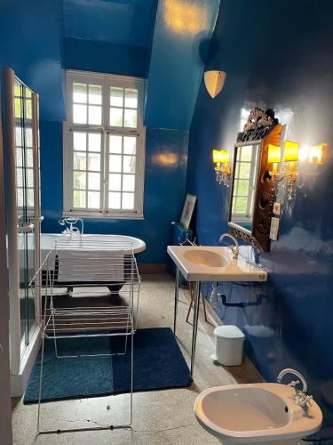 La salle de bains est pourvue de 2 lavabos et d'un mur bleu. dans l'établissement Our House, Château de la Boulaye, à Cerisy-la-Forêt