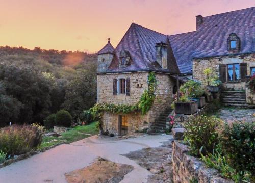 an old stone house with ivy on it at Domaine de Cantegrel - Gîtes de Charme et Suite Troglodyte en Périgord in Vitrac