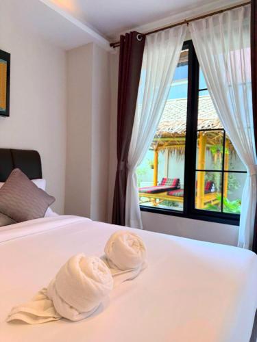 two towels sitting on top of a bed with a window at Flora Hostel KhaoSok in Khao Sok