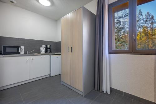 a kitchen with white cabinets and a window at Auberge de la Gravière in Orcières