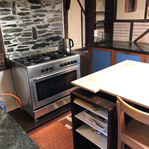 Il comprend une cuisine avec une cuisinière et un mur en pierre. dans l'établissement Our House, Château de la Boulaye, à Cerisy-la-Forêt