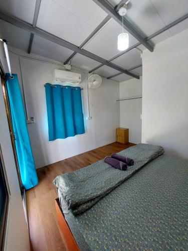 a bedroom with a bed and a blue curtain at AioonHomestay Single Room in Ban Bang Bao