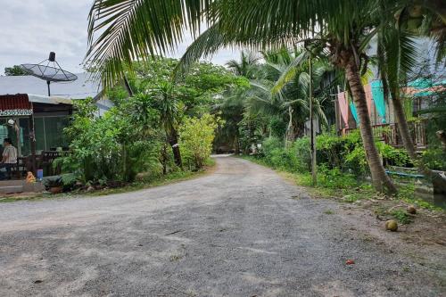 a dirt road with palm trees on the side of a street at Ruentonnum Amphawa in Amphawa