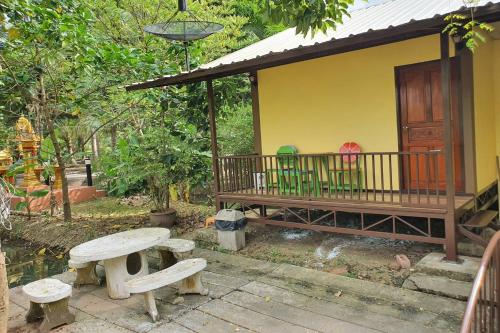 a picnic table and benches in front of a house at Ruentonnum Amphawa in Amphawa
