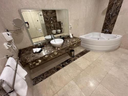 a bathroom with a sink and a tub and a mirror at Tolip Olympic International City in New cairo