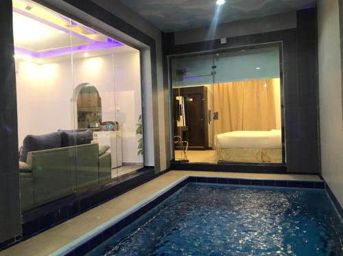 a pool in a room with a couch and a bedroom at شاليهات رميس للعائلات in Abha
