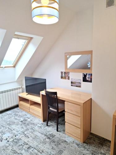 an attic office with a desk and a television at Dom na Wyłączność z Wanną z Hydromasażem, Sauną i Basenem in Mucharz