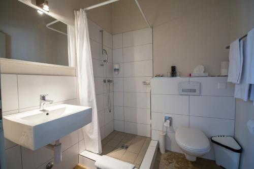 a white bathroom with a sink and a toilet at Apart Hotel Wetterhorn in Hasliberg