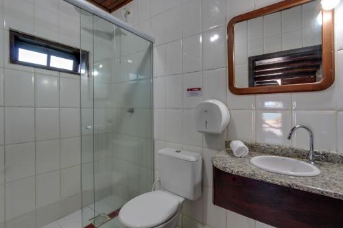 a bathroom with a toilet and a sink and a mirror at Pousada dos Ingleses in Bombinhas