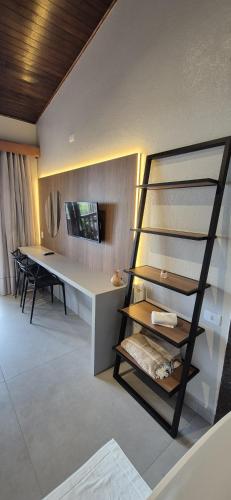 a room with a desk and a table with a shelf at Pousada dos Ingleses in Bombinhas