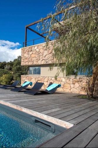une maison avec une piscine et des chaises longues sur une terrasse dans l'établissement Villa Standing Palombaggia 10 personnes vue mer, piscine, à Porto-Vecchio