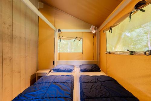 deux lits dans une petite pièce avec une fenêtre dans l'établissement Glamping Haure-Loire, à Sainte-Sigolène