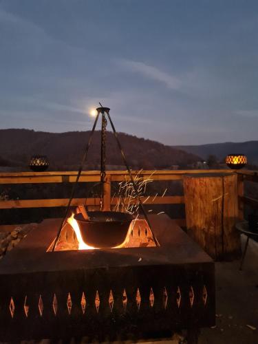 a fire pit sitting on top of a deck with the sunset at Conacul Fruntea cu ceru in Iloviţa