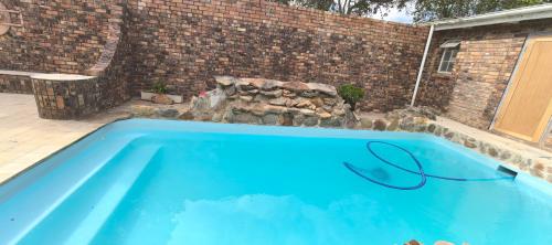 a large blue swimming pool next to a brick wall at Calming Waters Guesthouse in Grahamstown