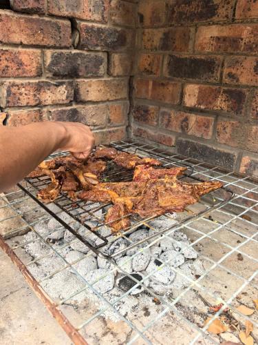 a person is cooking food on a grill at Calming Waters Guesthouse in Grahamstown