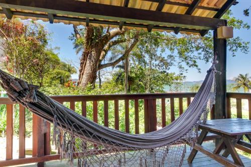 a hammock on a deck with a table at Pousada dos Ingleses in Bombinhas