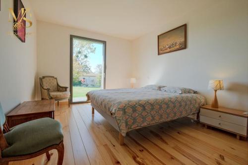 une chambre avec un lit, une chaise et une fenêtre dans l'établissement Maison Moderne avec Piscine au Cœur des Vignes, à Bergerac