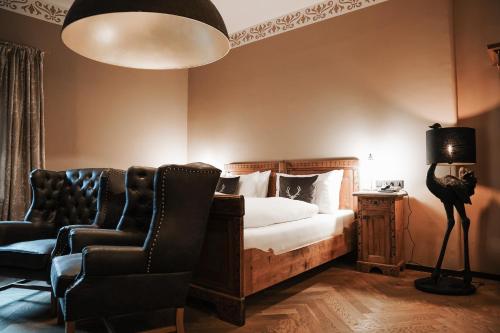 a bedroom with a bed and two chairs and a lamp at Boutiquehotel Weisses Rössl in Innsbruck