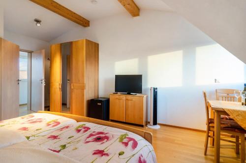 a bedroom with a bed and a tv and a table at Pension Zum Talhof in Reichenau