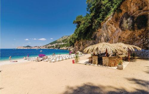 a beach with a straw umbrella and chairs and the ocean at Nice Apartment In Molunat With Wifi in Molunat