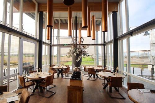a restaurant with tables and chairs and large windows at Dobberhuisje in IJsselstein