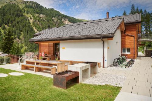 a cabin with a picnic table and benches in the yard at Reka-Feriendorf Zinal in Zinal