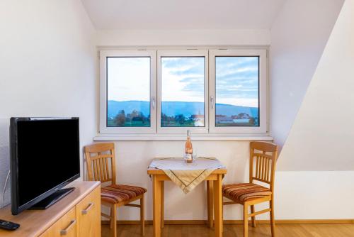 a living room with a table and two chairs and a television at Pension Zum Talhof in Reichenau
