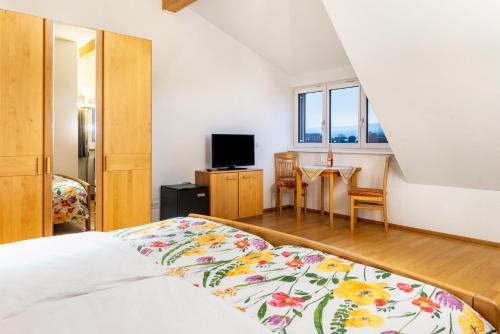 a bedroom with a bed and a table with chairs at Pension Zum Talhof in Reichenau