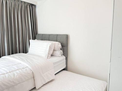 a bed with white sheets and pillows next to a window at The Jeewel of La Casa IV in Surabaya