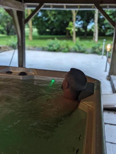 un homme dans un bain à remous avec la tête dans l'eau dans l'établissement AU NID DOUILLET DE LA FERME CHAUVET, à Chantenay-Villedieu