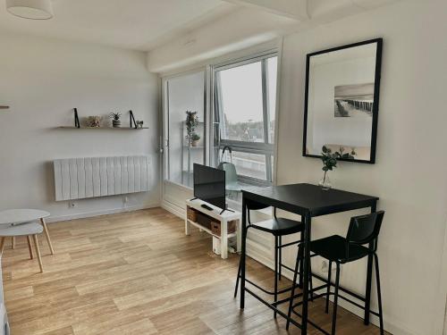 un salon avec une table et des chaises et une fenêtre dans l'établissement Sydney - studio avec loggia, accès direct plage, à Courseulles-sur-Mer
