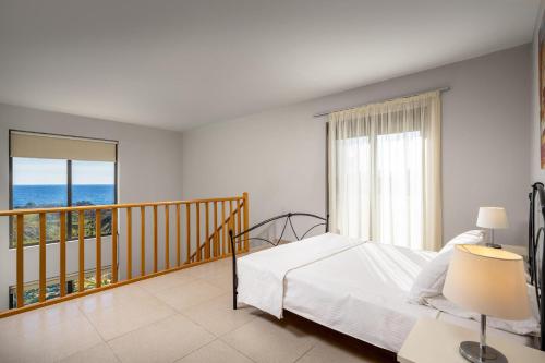 a bedroom with a bed and a balcony with the ocean at Gonos Villas in Asklipiḯon