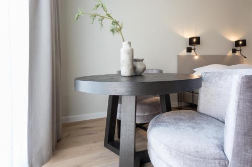 a table and a chair with a vase on it at Zeayou Zeeland - Studio's Zuidstraat 1 in Domburg