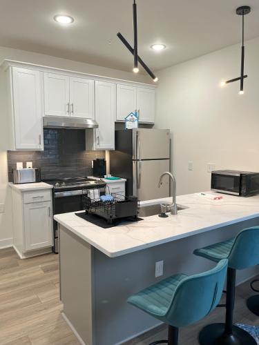 a kitchen with white cabinets and a counter with blue chairs at Church Hill Apt - TH02 - Tourist Homes of Richmond in Richmond