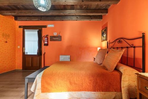 a bedroom with orange walls and a large bed at Nogueira in Vega de Logares