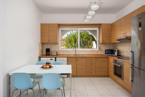 a kitchen with a white table and blue chairs at Gonos Villas in Asklipiḯon