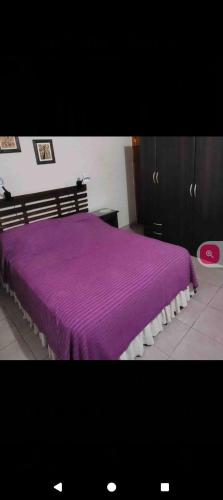 a bedroom with a purple bed with a purple blanket at La rana alquiler temporal in Reyes