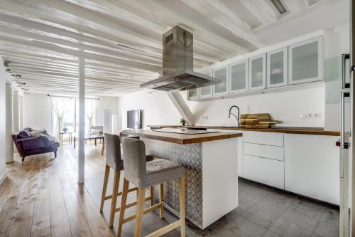 une cuisine avec des placards blancs et un comptoir avec des tabourets de bar dans l'établissement Le Lotus - Spacious & Central - Opéra, à Paris