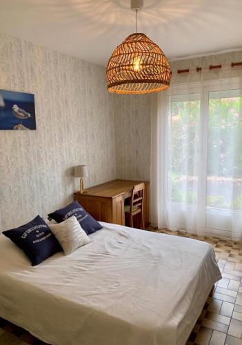 une chambre avec un lit, un bureau et un lustre dans l'établissement Villa Rose des Sables, à Andernos-les-Bains