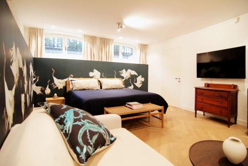 a bedroom with a bed and a couch and a tv at Spacious Suite at Park and Museum in Amsterdam