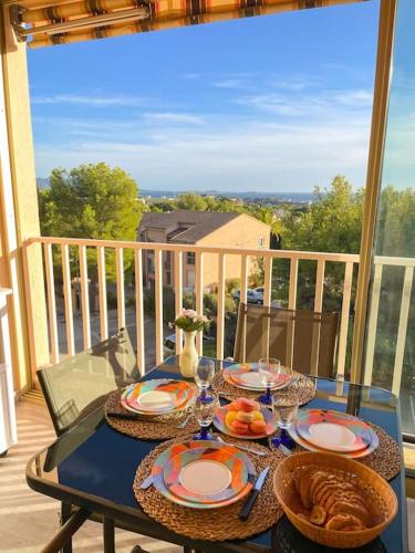 une table avec des assiettes de nourriture sur un balcon dans l'établissement Charmant T2 avec terrasse vue mer, à Bandol
