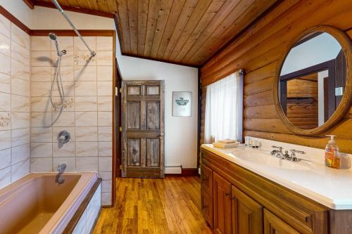 un bagno con vasca, lavandino e specchio di Eagle River Retreat a Eagle River