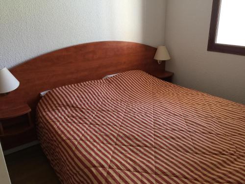 une chambre avec un lit avec une tête de lit en bois dans l'établissement ski piscine et fitness à la Mongie, à Bagnères-de-Bigorre