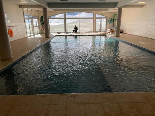 un bassin d'eau dans un bâtiment où se trouve une personne assise dans l'établissement ski piscine et fitness à la Mongie, à Bagnères-de-Bigorre