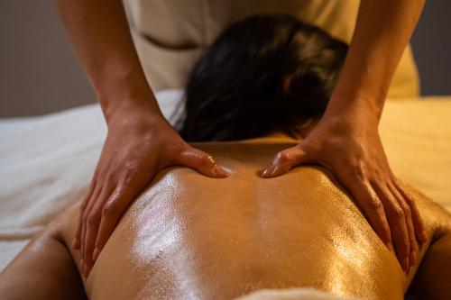 a woman laying on a bed with her hands on her back at Armon Greenblu Hotel & Wellness in Folgarida