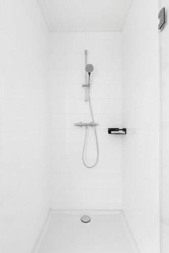 a shower in a white bathroom with a shower at Bed & Bike De Dorsvloer in Domburg