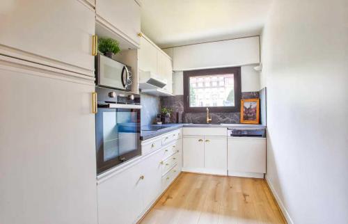 une cuisine avec des armoires blanches et une fenêtre dans l'établissement Charming Apt w- large Balcony - 2BD-4P - Deauville, à Deauville