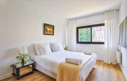 une chambre blanche avec un grand lit et une fenêtre dans l'établissement Charming Apt w- large Balcony - 2BD-4P - Deauville, à Deauville